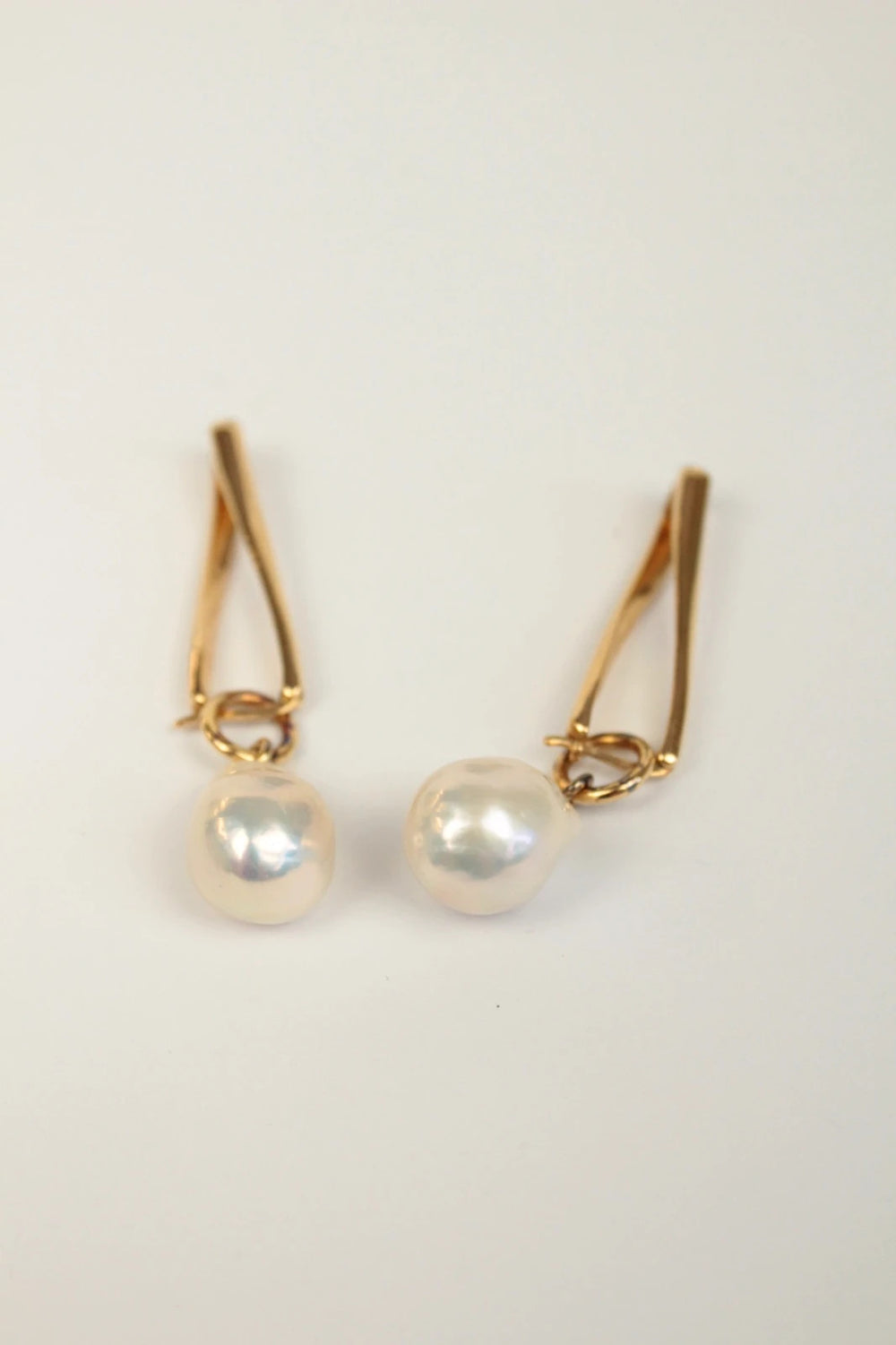 Missoma gold twisted drop earrings with baroque pearl and high-shine link hoop design.