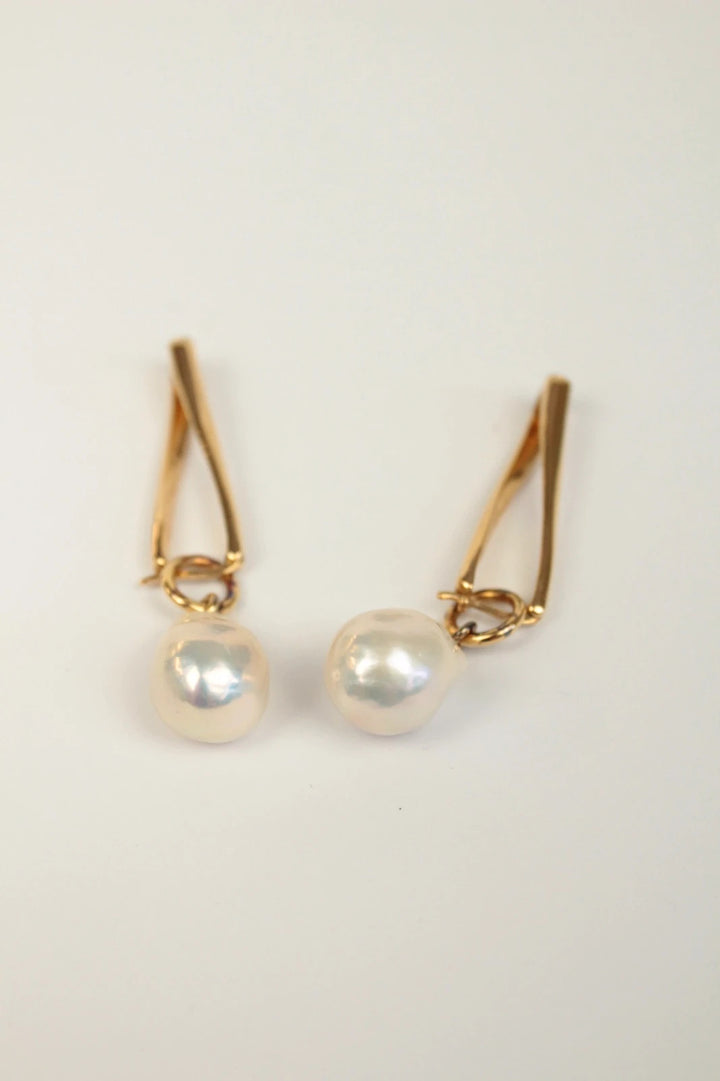 Missoma gold twisted drop earrings with baroque pearl and high-shine link hoop design.