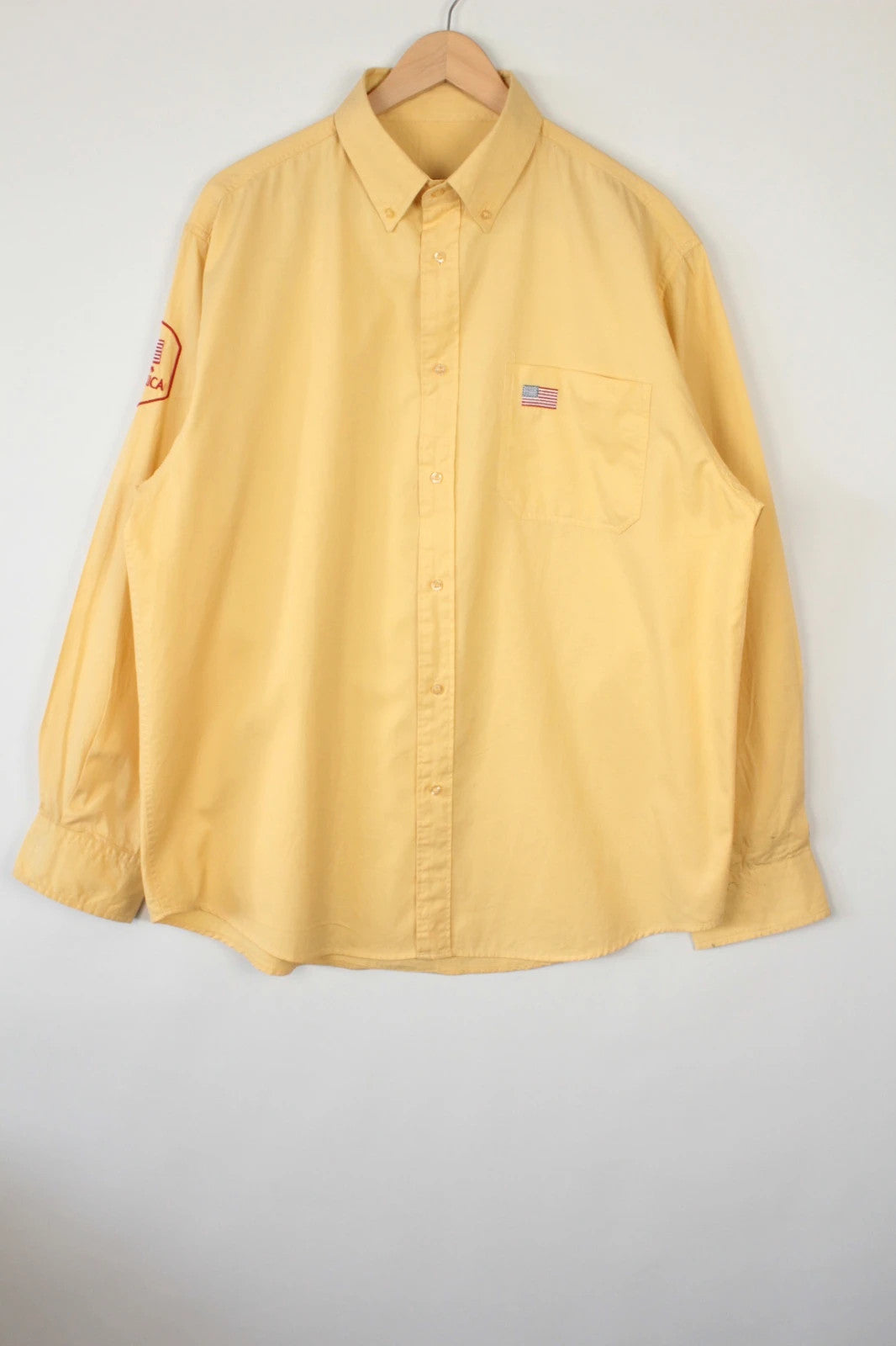 Vintage USA yellow Oxford shirt with embroidered American flag and retro patch on sleeve.