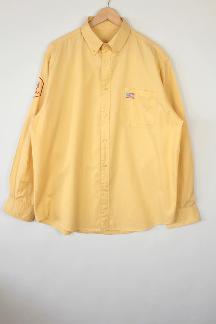 Vintage USA yellow Oxford shirt with embroidered American flag and retro patch on sleeve.