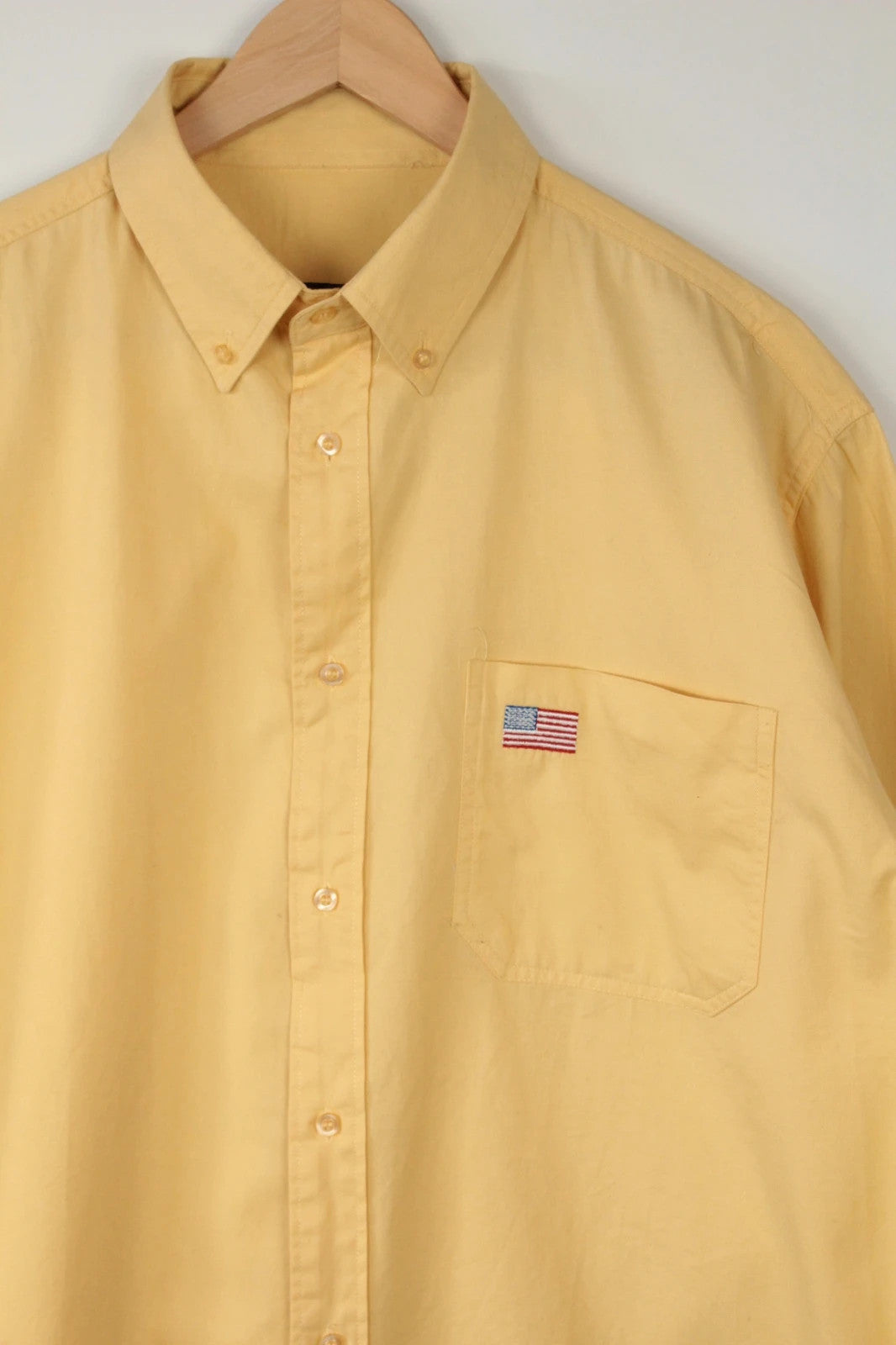 Vintage USA yellow Oxford shirt with embroidered American flag and retro patch on sleeve.