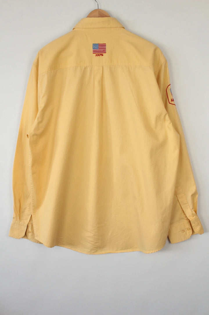 Vintage USA yellow Oxford shirt with embroidered American flag and retro patch on sleeve.