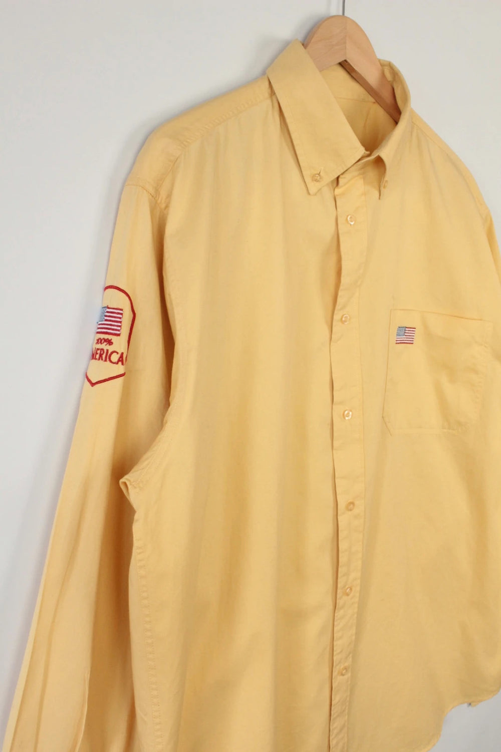 Vintage USA yellow Oxford shirt with embroidered American flag and retro patch on sleeve.