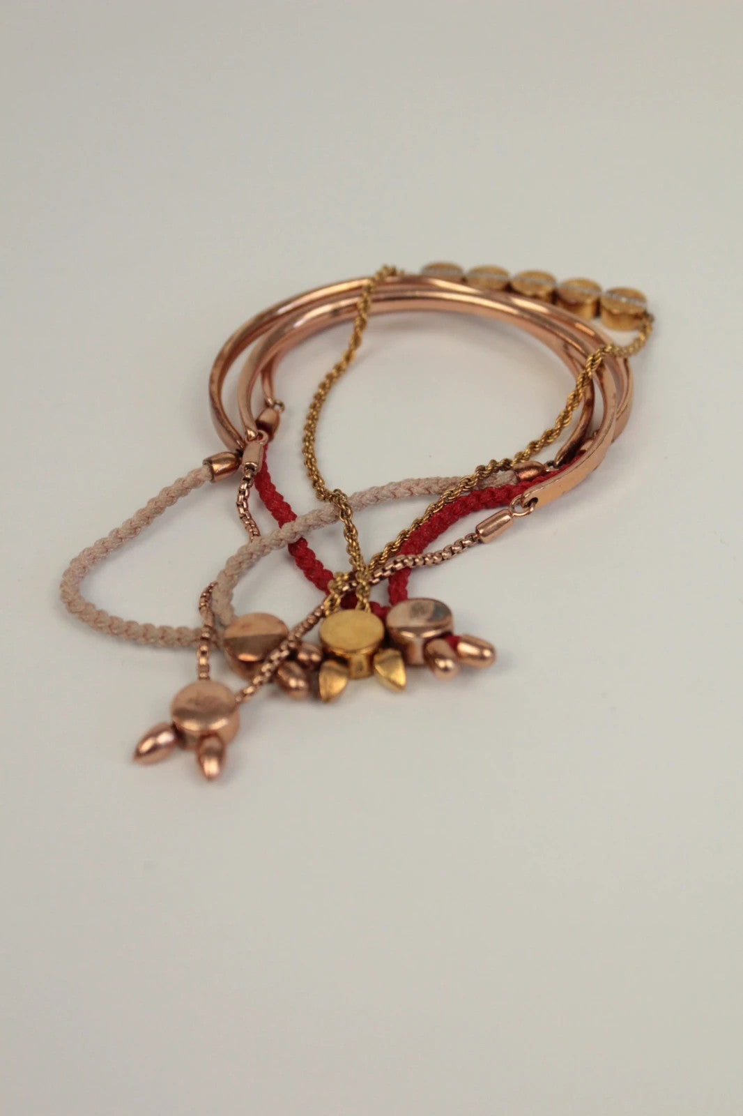 Joy stackable bracelet set rose gold tone with red and pink textile cords.