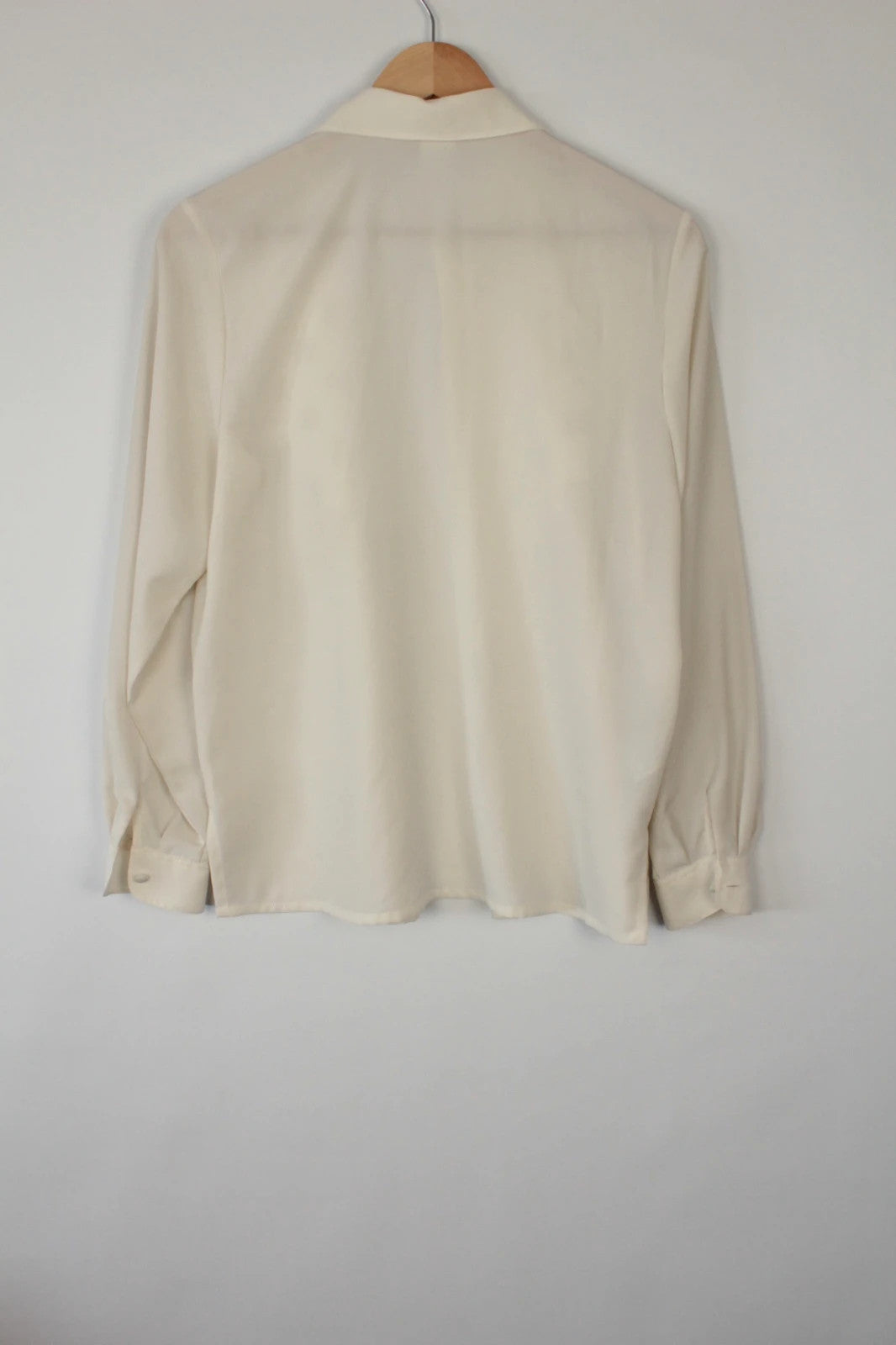 Country Casuals cream tunic blouse with embroidered checkerboard bib and long sleeves.