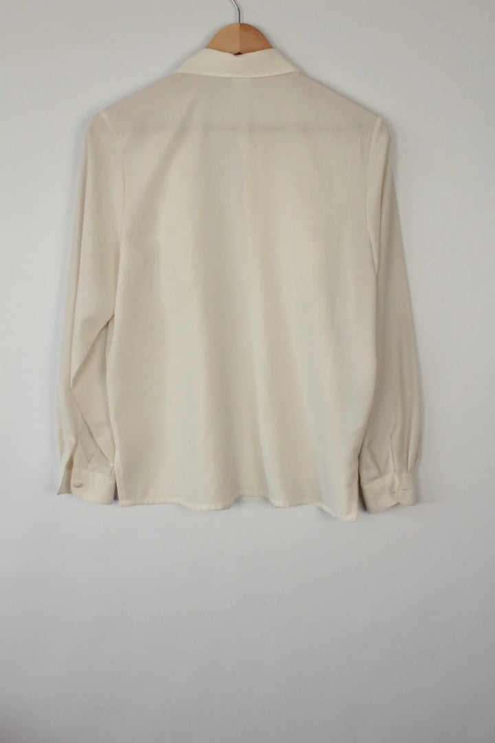Country Casuals cream tunic blouse with embroidered checkerboard bib and long sleeves.
