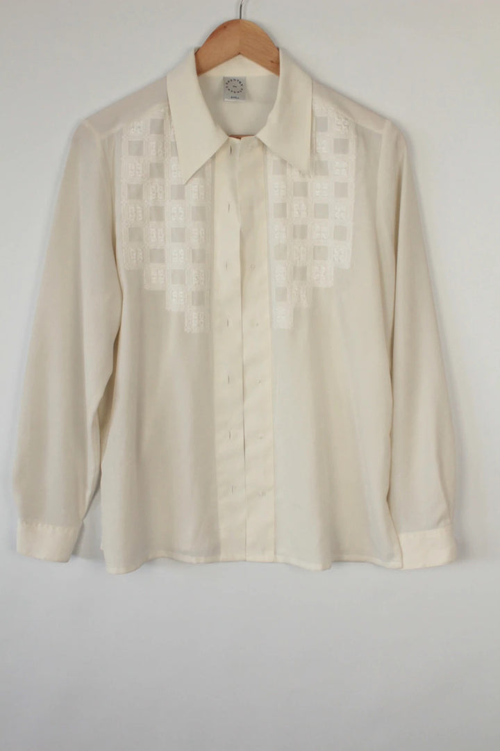 Country Casuals cream tunic blouse with embroidered checkerboard bib and long sleeves.
