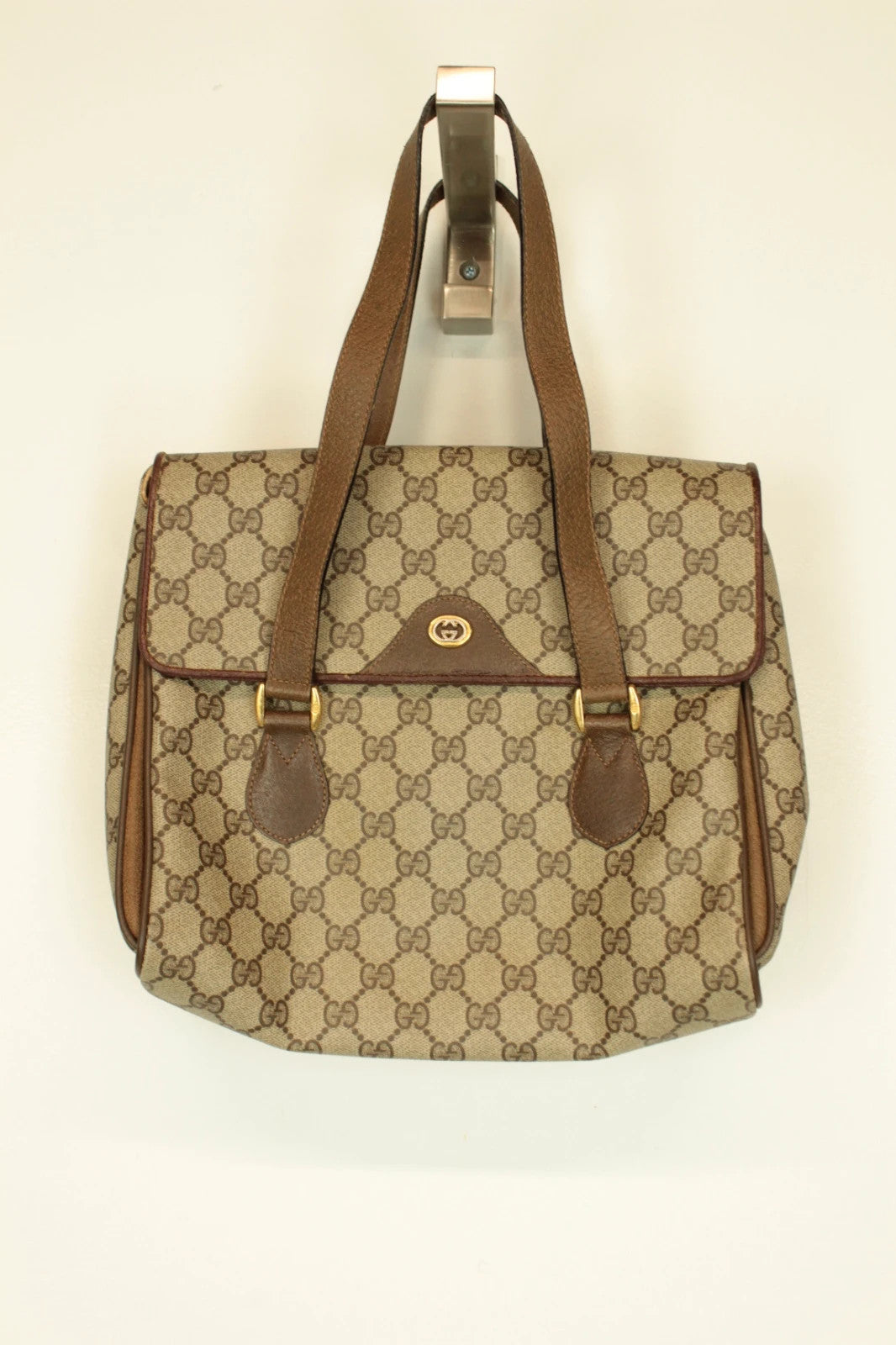 Gucci beige GG Plus Supreme monogram handbag with brown leather trim and gold-tone emblem.
