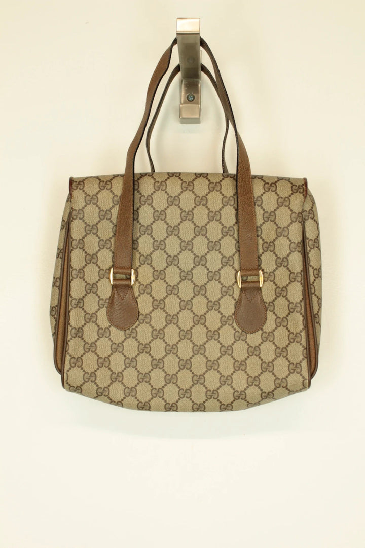 Gucci beige GG Plus Supreme monogram handbag with brown leather trim and gold-tone emblem.