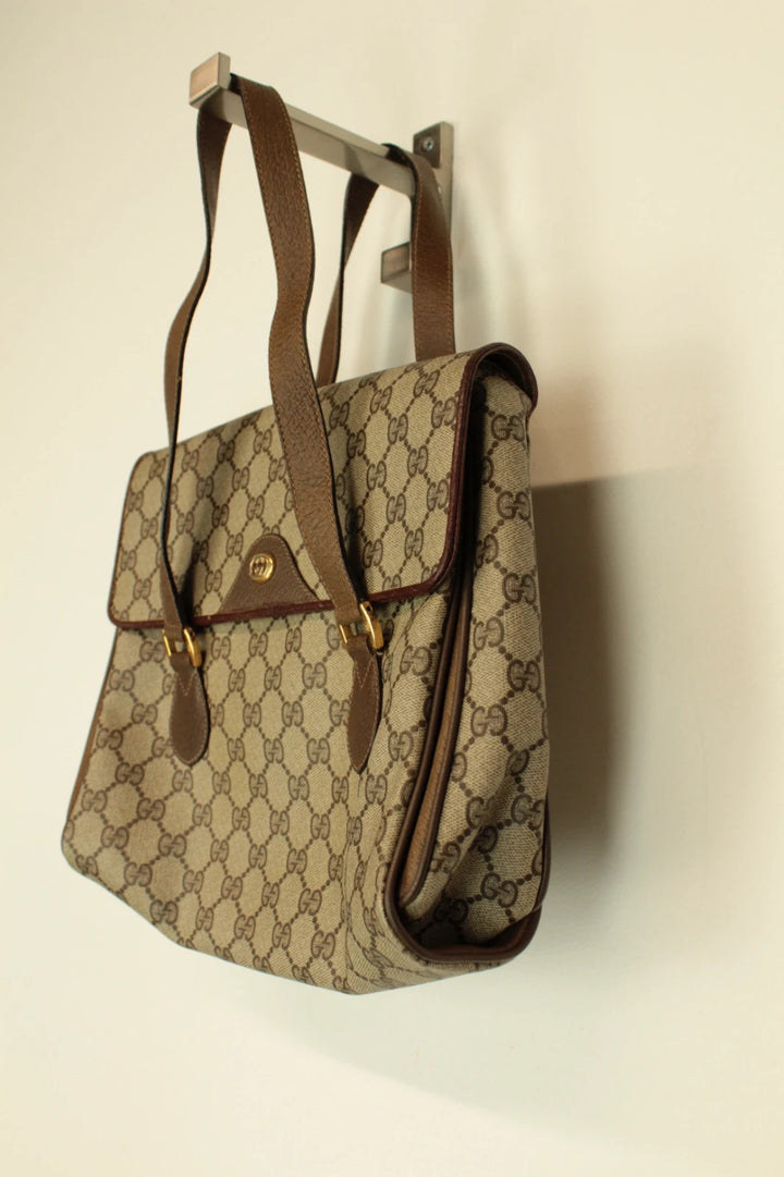 Gucci beige GG Plus Supreme monogram handbag with brown leather trim and gold-tone emblem.