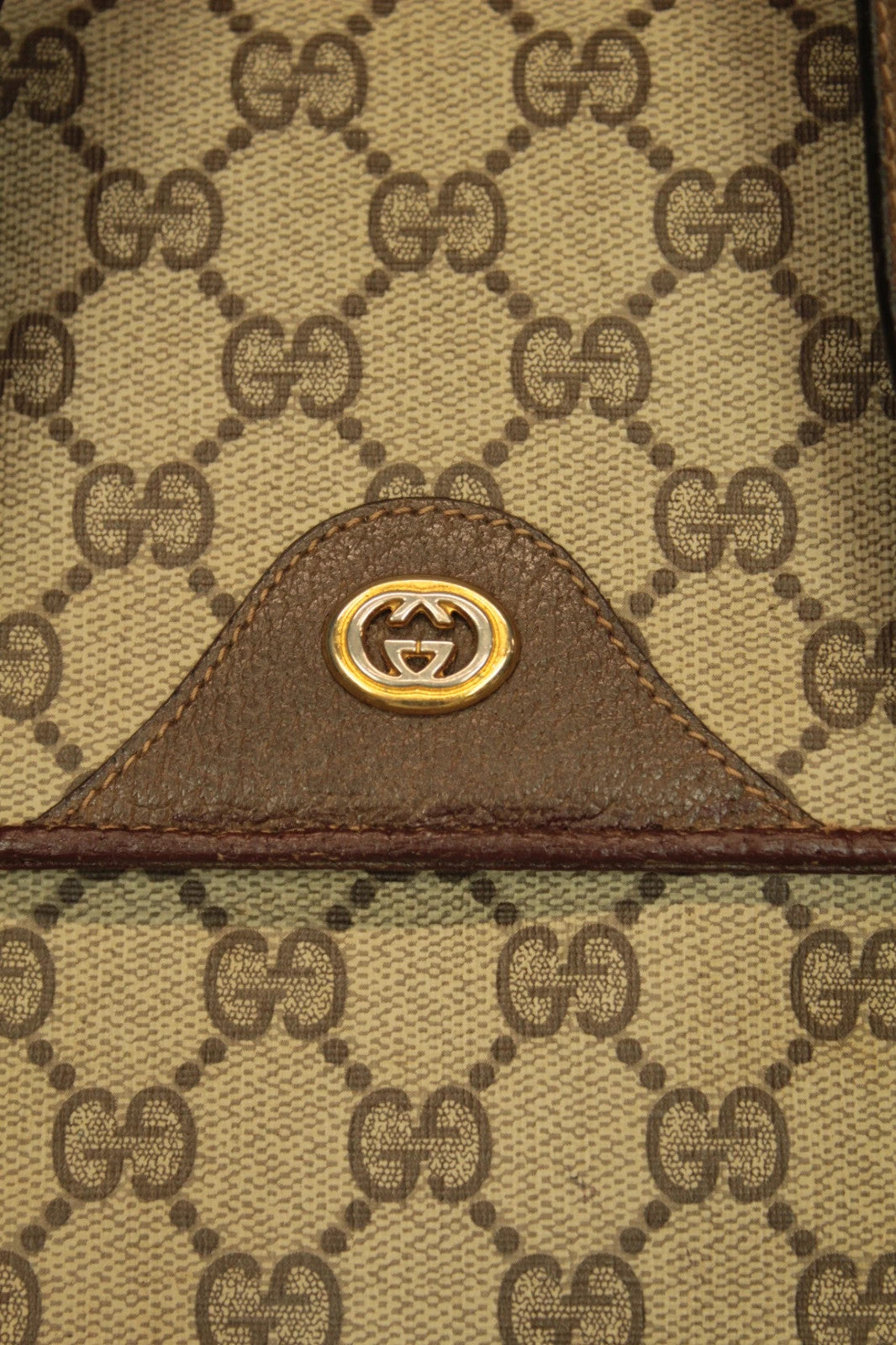 Gucci beige GG Plus Supreme monogram handbag with brown leather trim and gold-tone emblem.