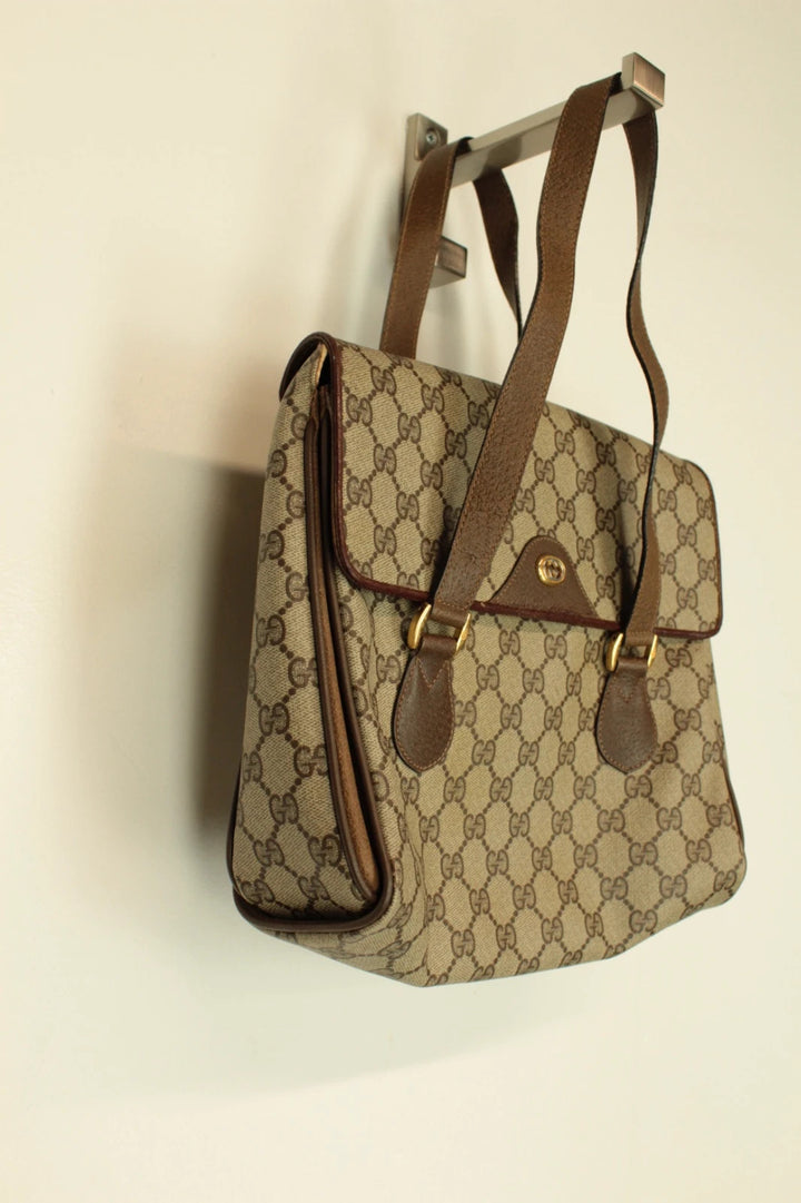 Gucci beige GG Plus Supreme monogram handbag with brown leather trim and gold-tone emblem.