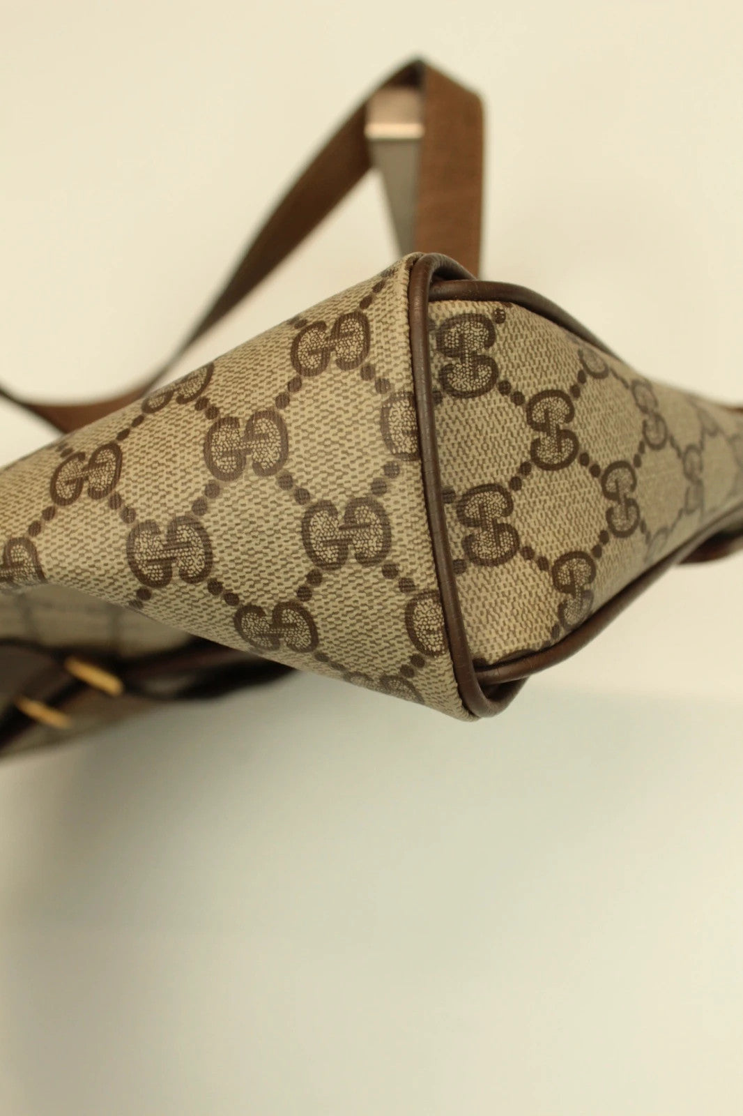 Gucci beige GG Plus Supreme monogram handbag with brown leather trim and gold-tone emblem.