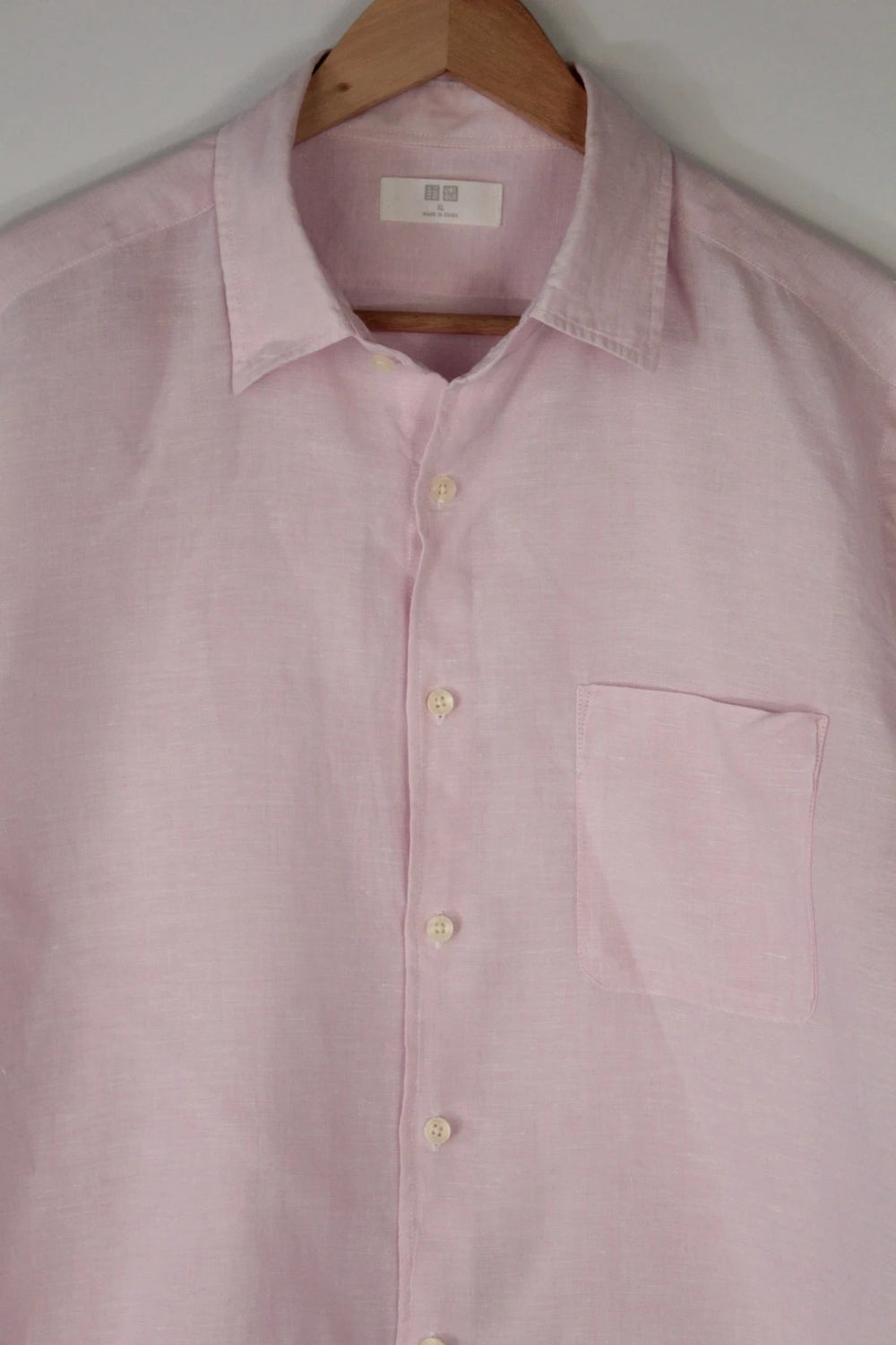 Uniqlo light pink long sleeve linen shirt with classic white buttons and chest pocket.