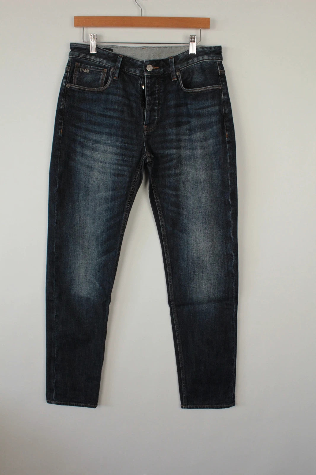Emporio Armani navy slim jeans with metal eagle logo and leather waist patch.