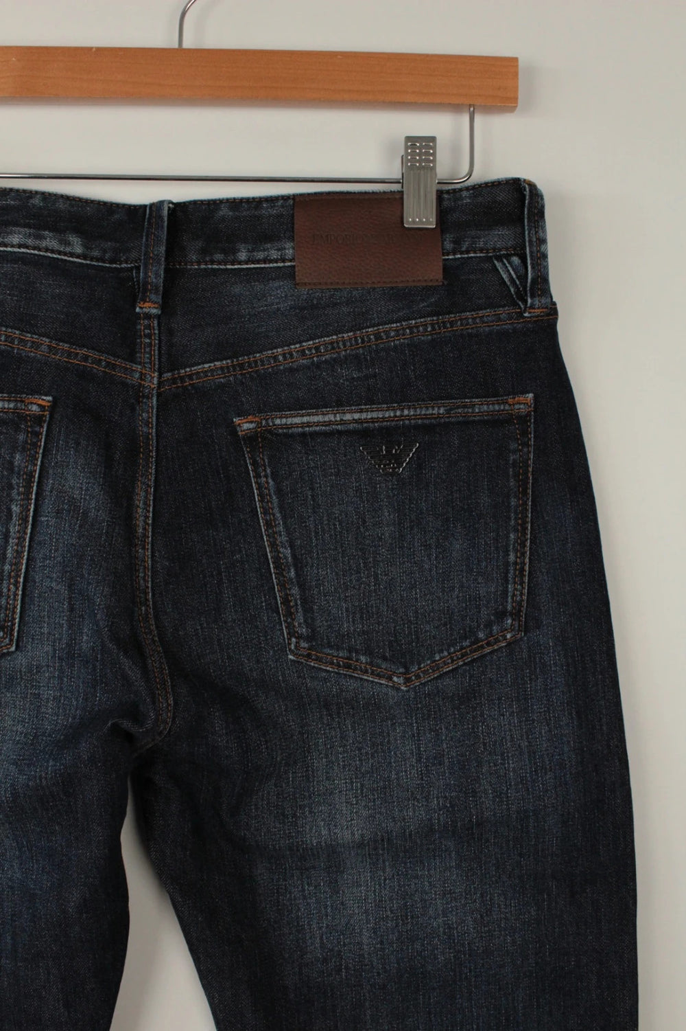 Emporio Armani navy slim jeans with metal eagle logo and leather waist patch.