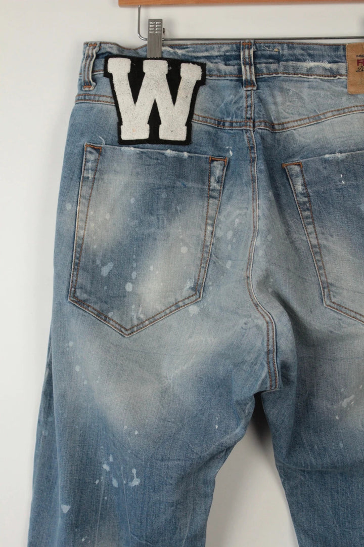 Adamus baggy jeans black and blue with bleach paint splatter and tan leather waistband patch.