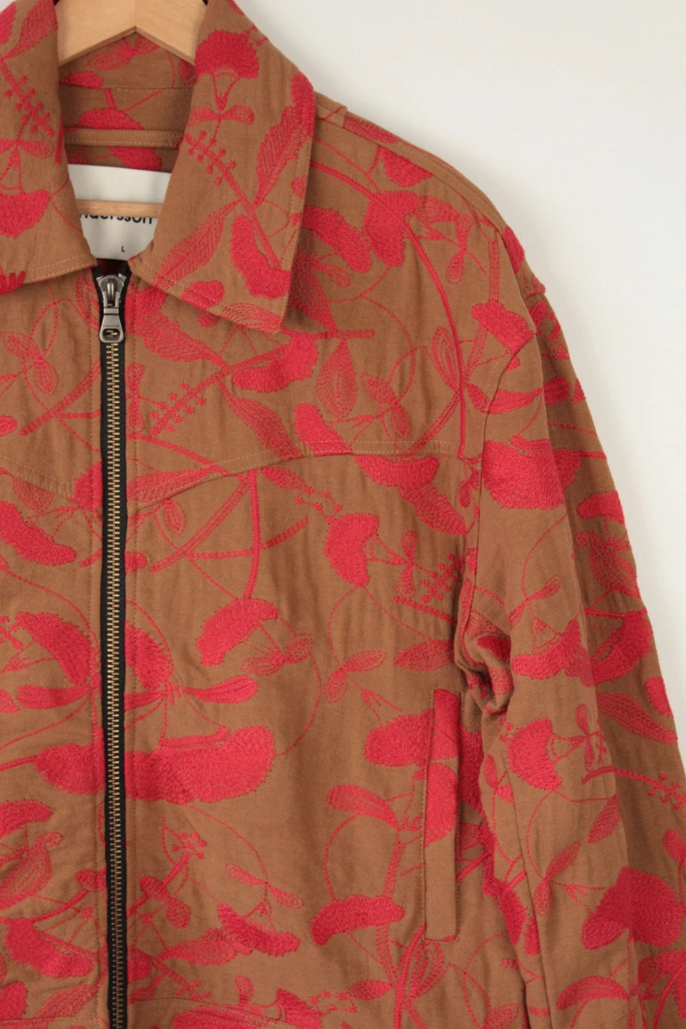 Andersson Bell brown zip-up jacket with vibrant red floral embroidery and logo rivets.