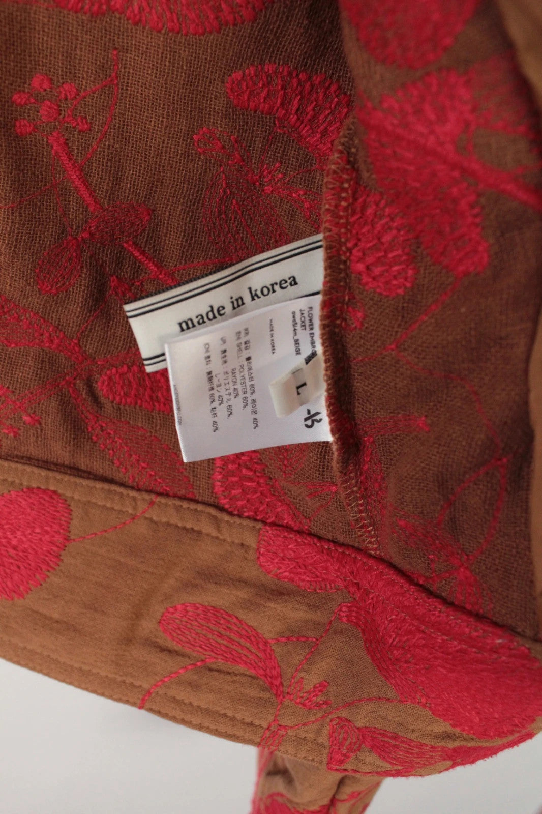 Andersson Bell brown zip-up jacket with vibrant red floral embroidery and logo rivets.