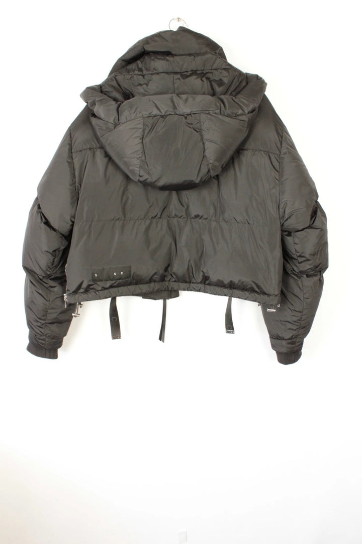 Shoreditch Ski Club black cropped puffer jacket with quilted matte shell and harness straps.