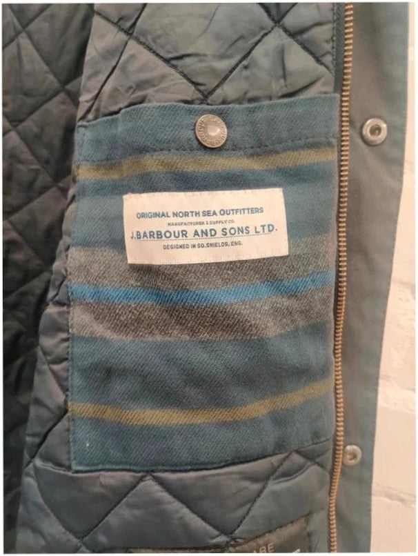 Barbour navy blouson wax jacket with quilted lining and Levi's denim pocket details.