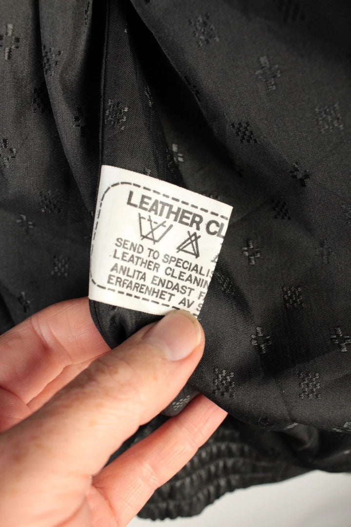 Vintage Dressing black leather bomber jacket with geometric panel stitching and multi-pocket design.