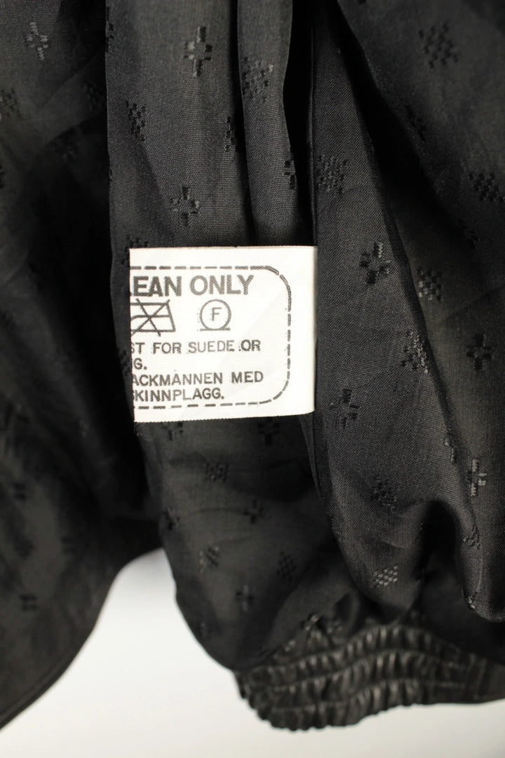 Vintage Dressing black leather bomber jacket with geometric panel stitching and multi-pocket design.