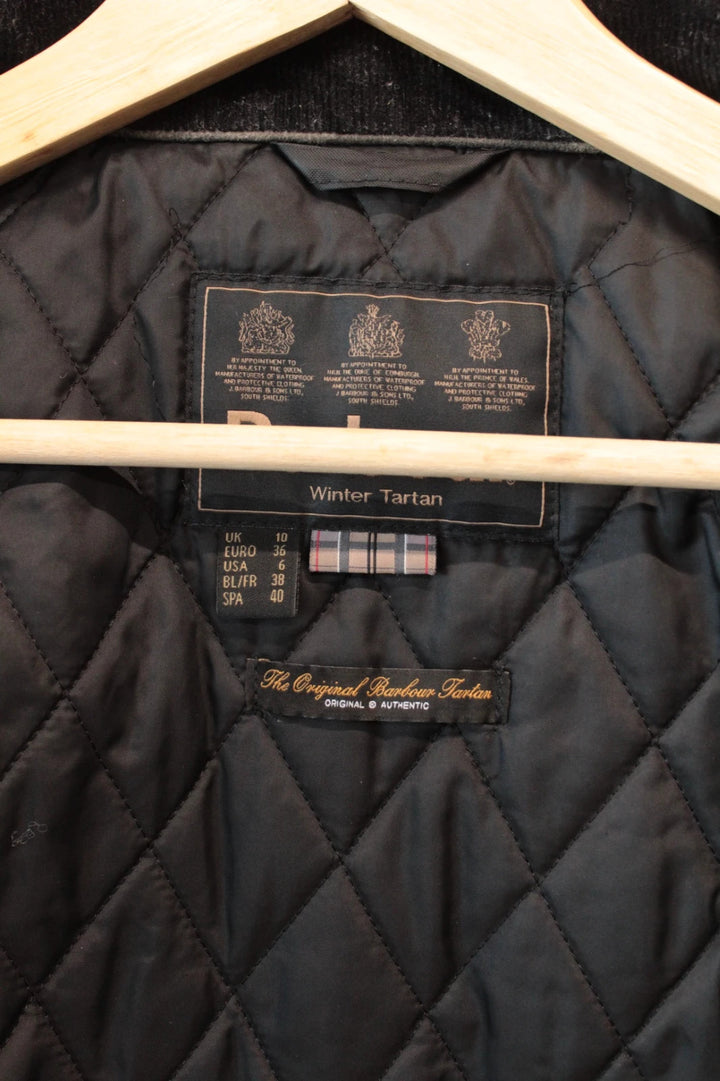 Barbour black waxed cotton jacket with tartan pattern and corduroy collar accent.
