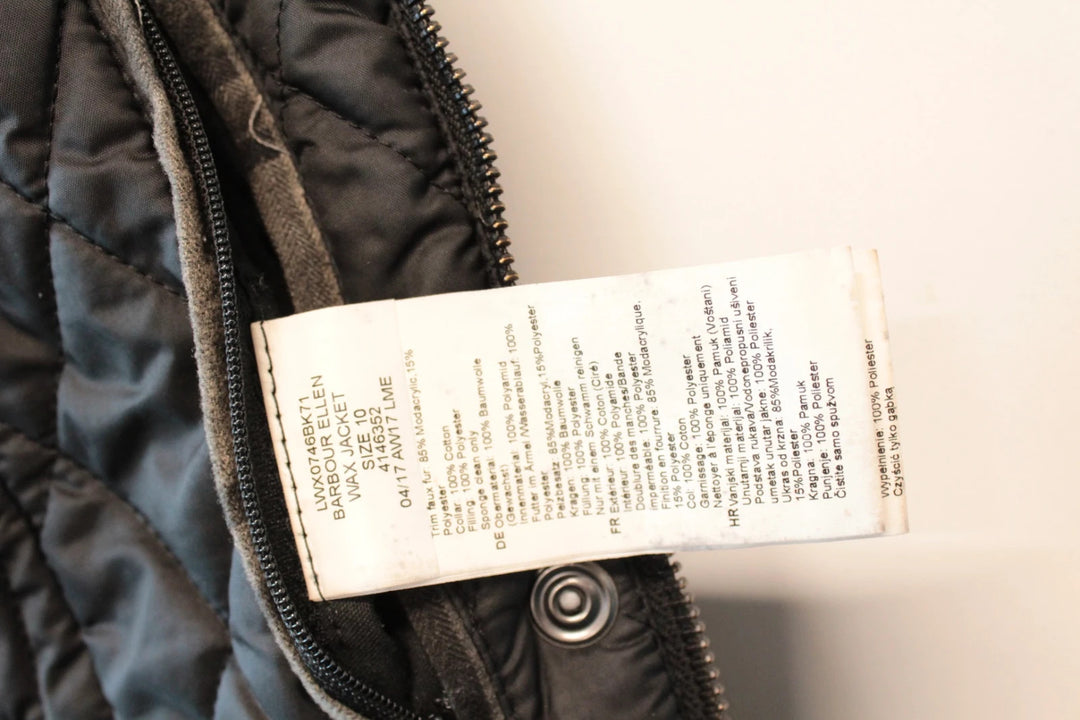 Barbour black waxed cotton jacket with tartan pattern and corduroy collar accent.